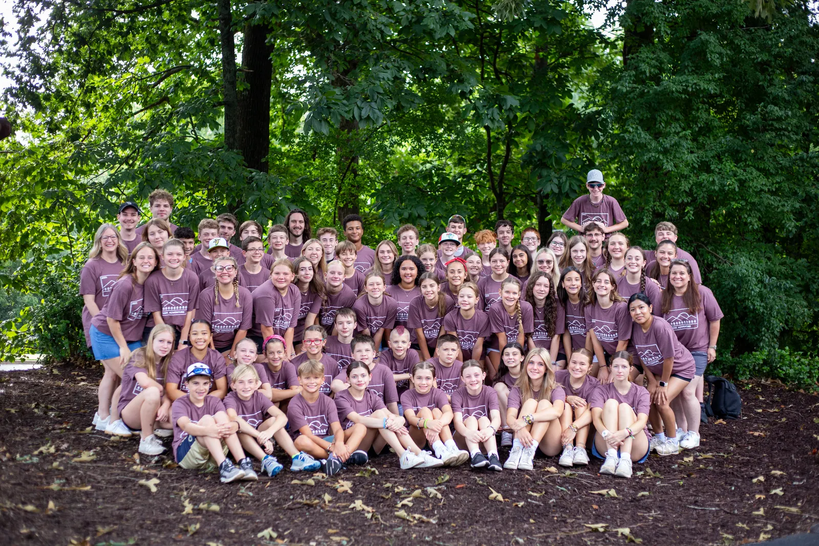 Large group of campers in matching purple shirts in the woods