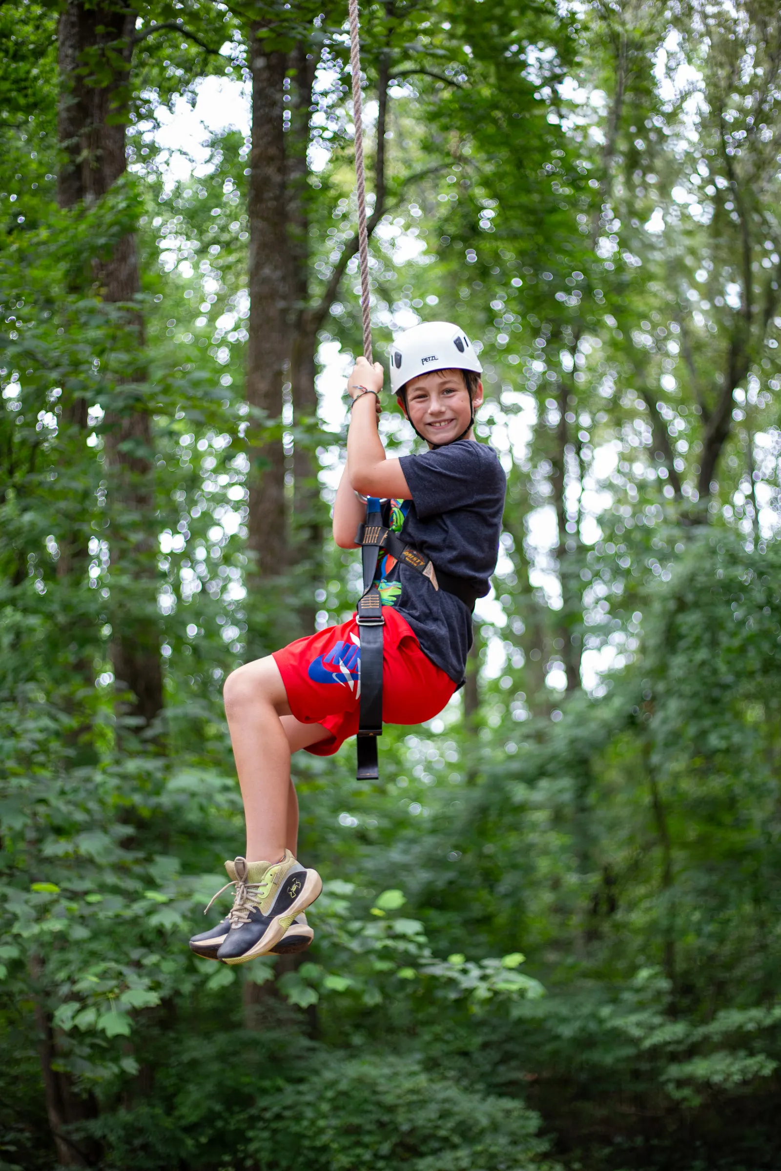 Camper riding the zipline through the trees